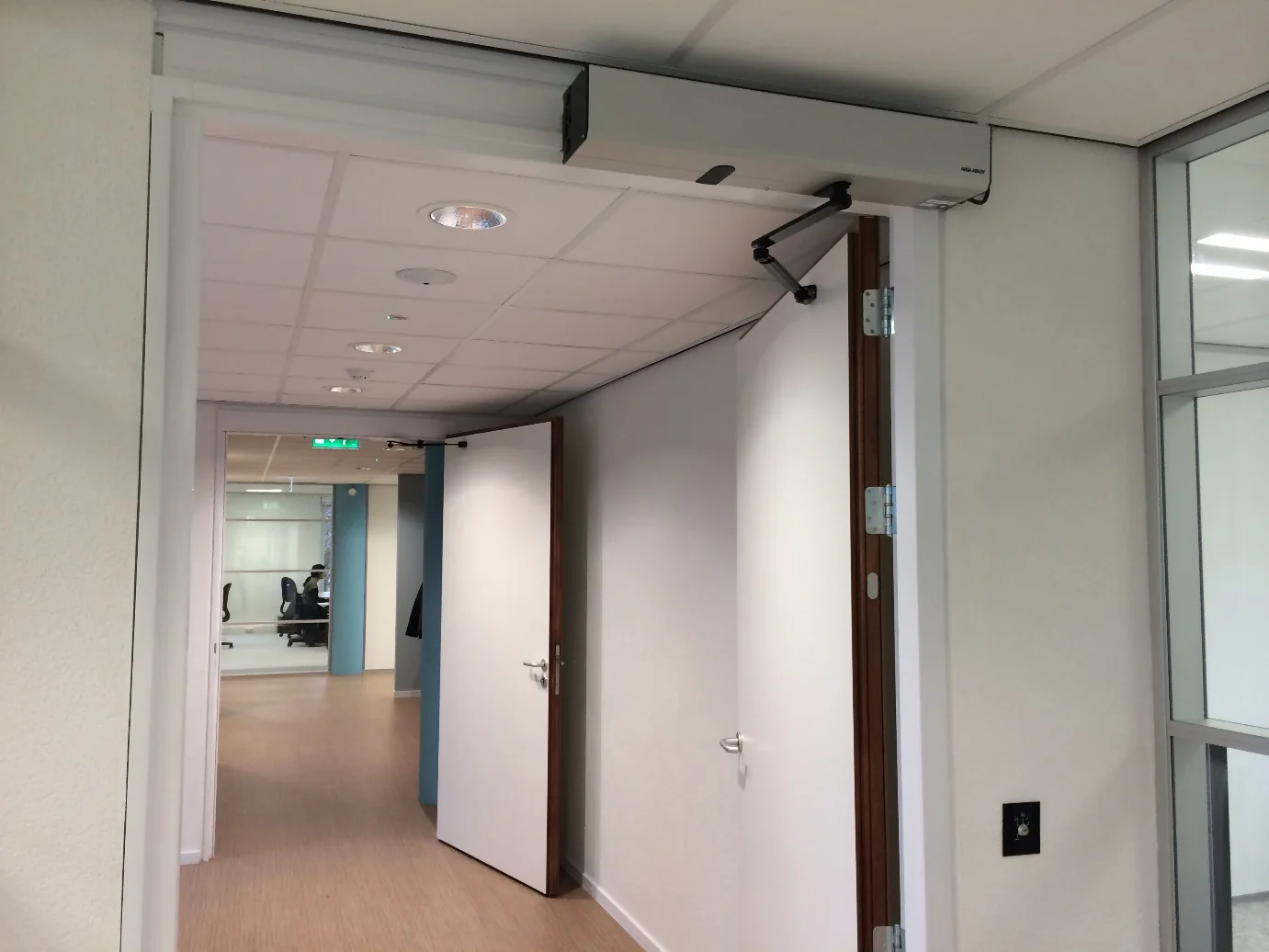 ASSA ABLOY SW200 draaideurautomaat boven een glazen deur
